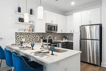 A kitchen with a island and a stainless steel refrigerator